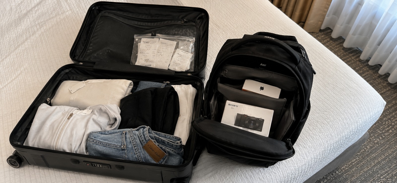 Mala organizada com eletrônicos na bagagem de mão e roupas separadas